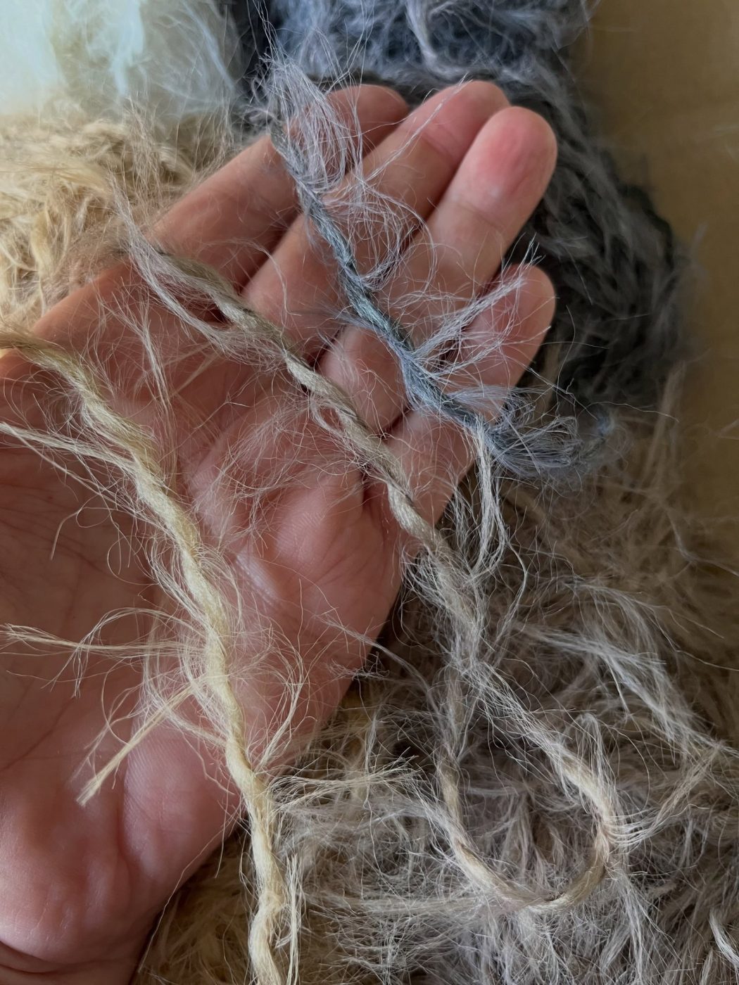 Hand met pluizig garen in zachte kleuren